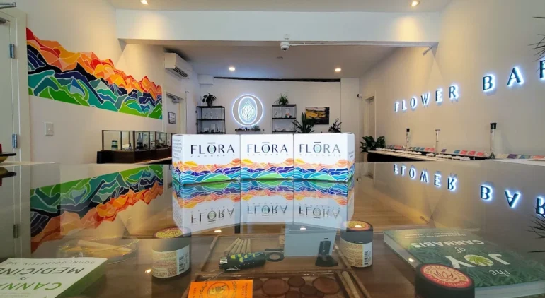 Branded boxes of flora cannabis sitting on a glass counter